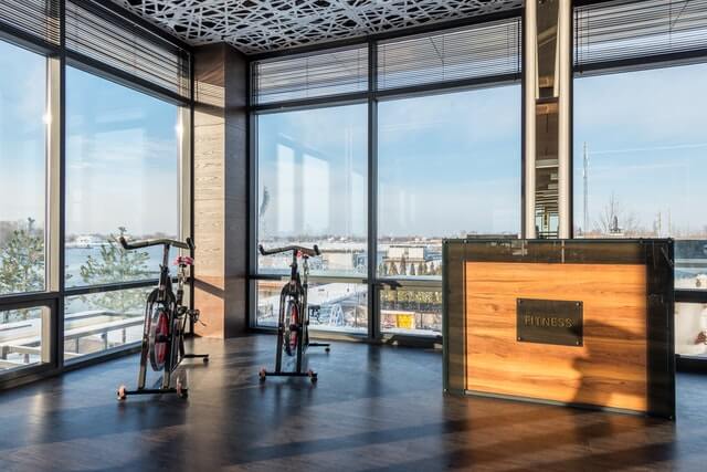 Advantages of Workplace Wellness Programs shown in a modern fitness studio with exercise bikes and a scenic view.