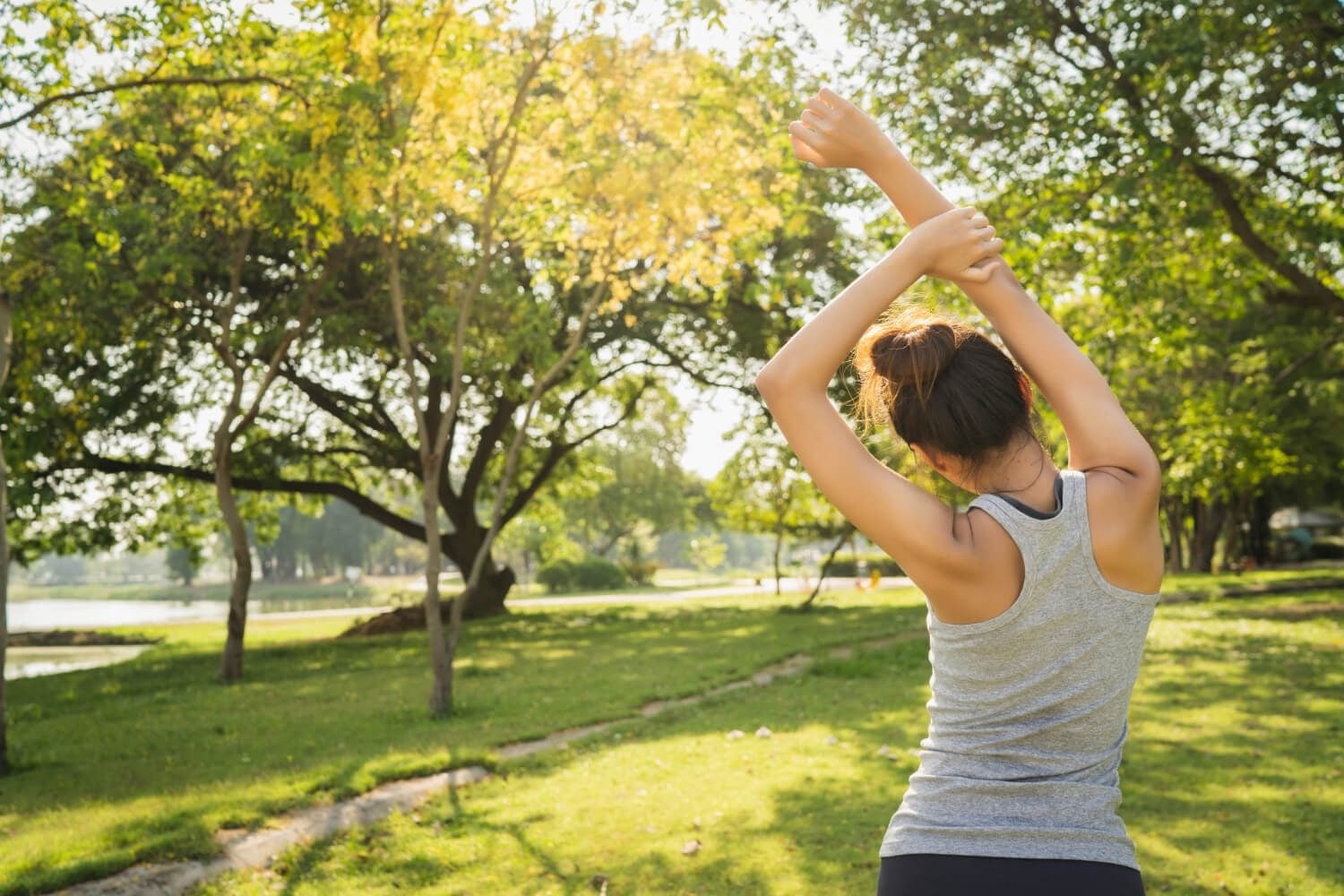 Daily Stretching Benefits shown with a woman stretching outdoors in a sunny, serene park setting.