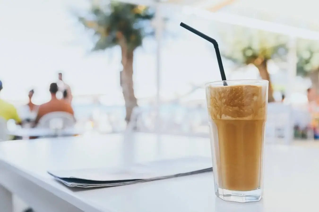 Signs to See a Nutritionist illustrated with a refreshing iced coffee on a bright outdoor cafe table.
