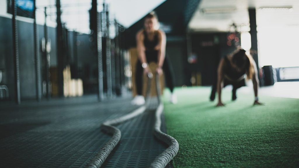 Two individuals engaging in intense gym exercises, symbolizing the challenges and guidance during a first personal training session.