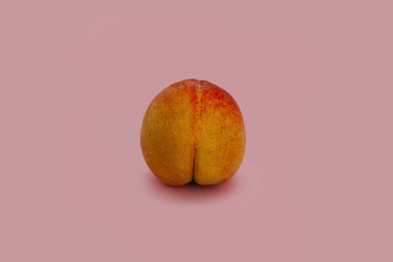 A fresh peach against a pink background, creatively symbolizing fitness tips for toning and maintaining a healthy physique.